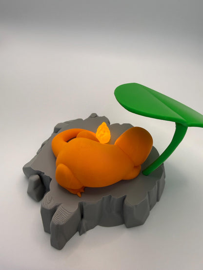 May include: An orange, cartoon-like figure with a curled tail rests on a gray, rocky platform. A small, glowing flame is near the figure's tail. A green leaf extends from the right side of the platform. The figure is a stylized representation of a Charmander.