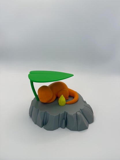 May include: A 3D-printed orange creature figurine resting on a gray rock-like base, with a green leaf overhead. A small yellow flame is next to the creature. The figurine is a stylized representation of a popular character.