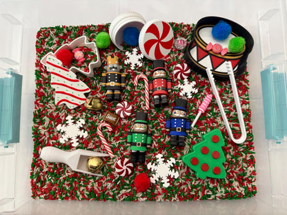 May include: A Christmas-themed sensory bin filled with red, green, and white rice. Includes toy nutcrackers, candy canes, snowflakes, a drum, and a Christmas tree-shaped cookie cutter. A fun and festive activity for children.