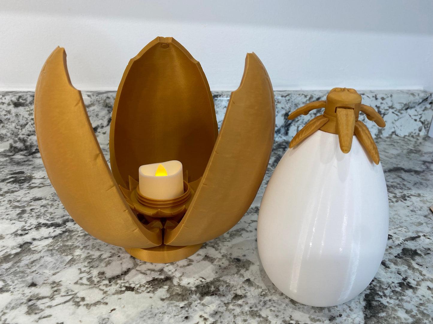 May include: A gold egg-shaped container with a candle inside, and a white egg-shaped container with a gold top.