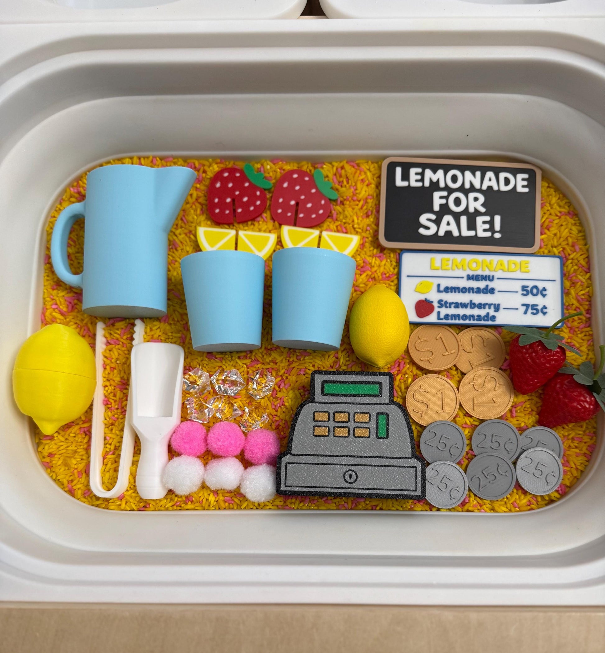 May include: A child's play set with a lemonade stand theme. Includes a blue pitcher, cups, lemons, strawberries, a cash register, play money, and a sign that reads "Lemonade for Sale!" and a menu.