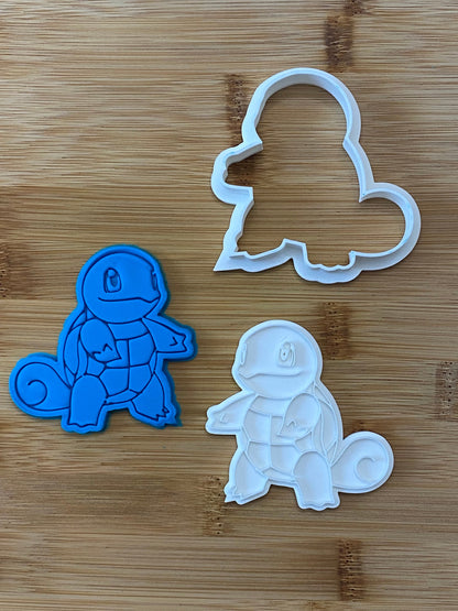 May include: Three cookie cutters, two are Squirtle Pokemon, one is a solid outline of Squirtle. The Squirtle cutters are blue and white plastic.